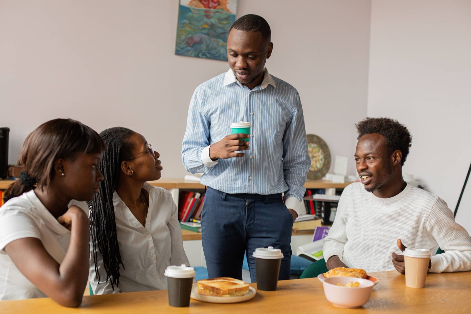 Colleagues share lunch and coffee around a table on their break